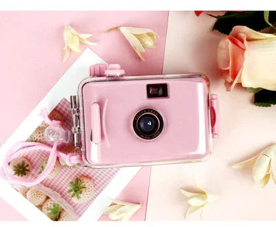 Pink retro-style instant camera with clear case, floral background, perfect for selfies and party photos
