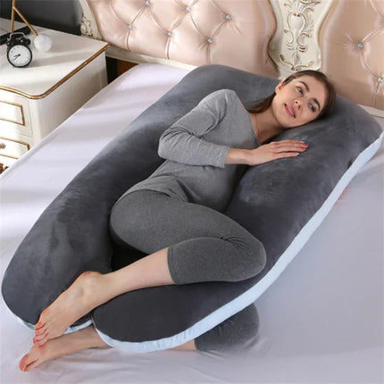 Gray U-shaped body pillow with white trim, supporting pregnant woman in bed for comfort and sleep