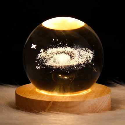 Glowing galaxy crystal ball with starry design on wooden base, ambient night light decor