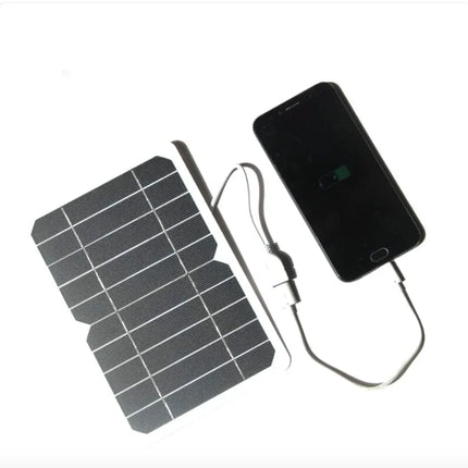 Portable solar phone charger with black panel, charging smartphone via USB cable, ideal for outdoor use