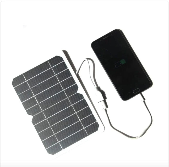 Portable solar phone charger with black panel, charging smartphone via USB cable, ideal for outdoor use