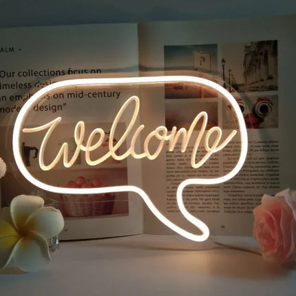 Glowing white neon 'Welcome' sign in speech bubble shape, modern home decor with warm light