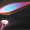 Colorful LED projector lamp casting rainbow light beam on dark surface, modern ambient lighting design