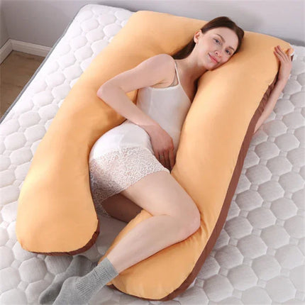 Yellow U-shaped body pillow with brown trim, supporting side sleeper on mattress