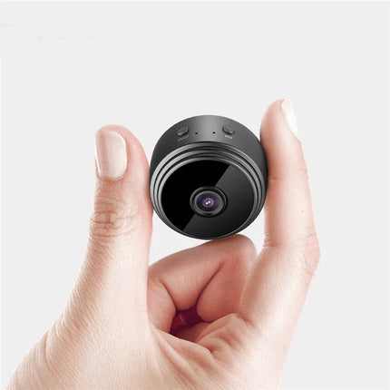 Compact black mini security camera with lens and mode button, held in hand for size reference