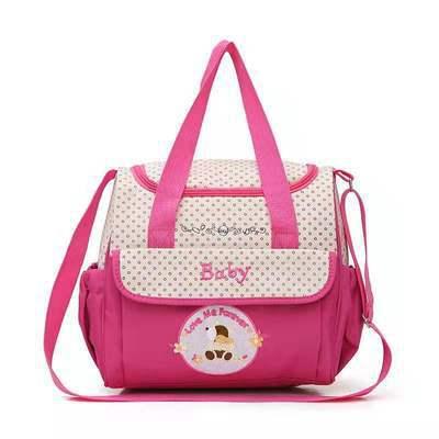 Pink baby diaper bag with polka dot design, front pocket labeled 'Baby', and cute bear patch for nursery essentials
