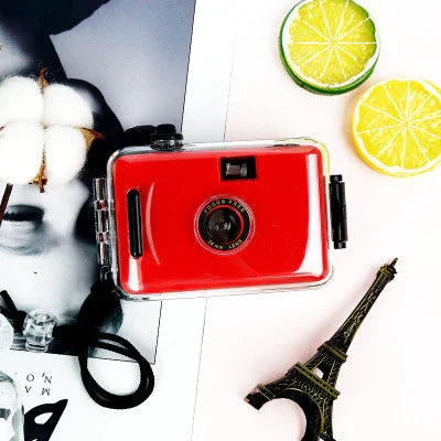 Red waterproof disposable camera with black strap, styled with lime slices and Eiffel Tower mini
